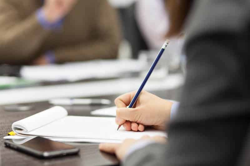 a person taking hand written notes at a conference